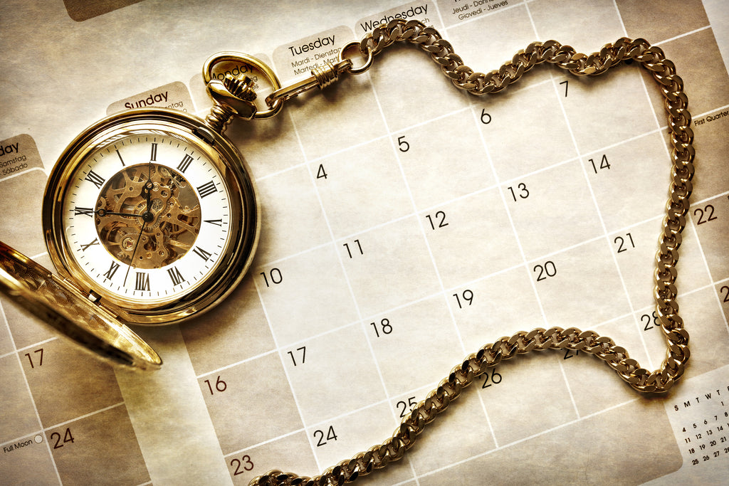 Gold Pocket Watch on a Calendar