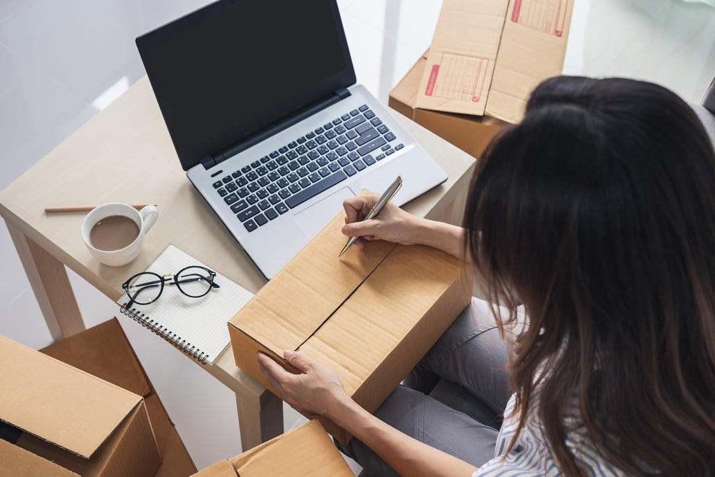 Woman Writing on a Package and Working at the Computer